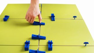 Prikaz ročnega zategovanja Easytiler klina in spojke na rumenih ploščicah.